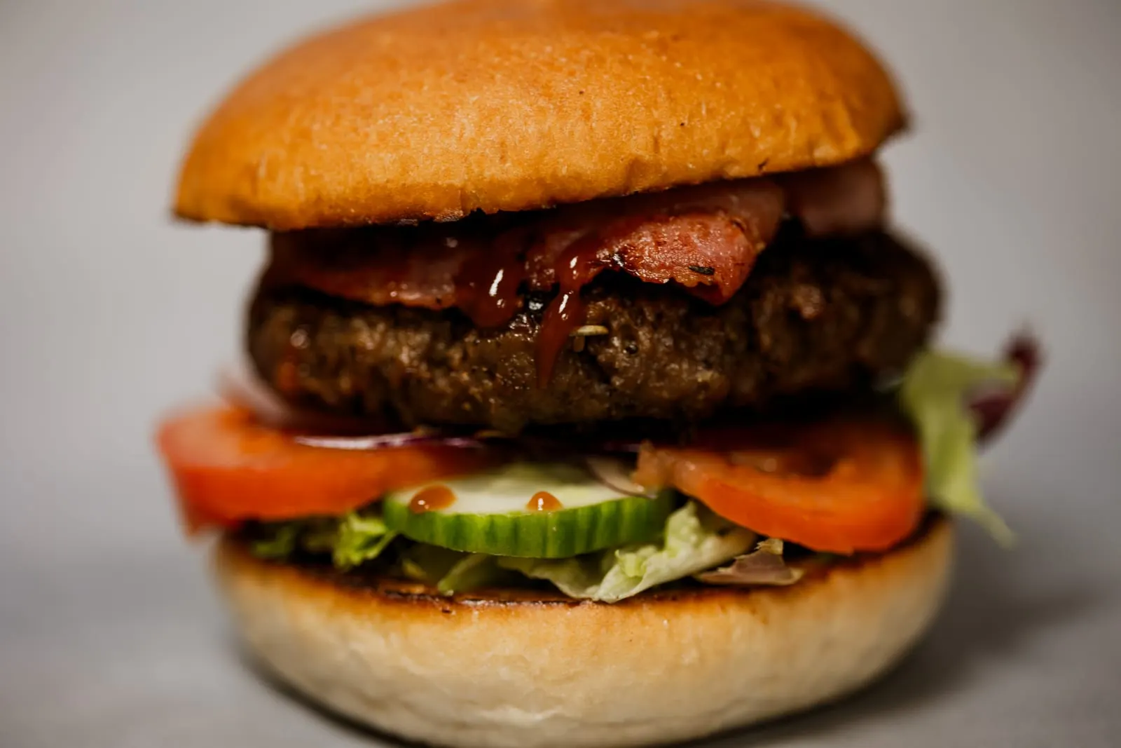 Hamburger Anderz met spek, saus, tomaat, komkommer en sla op een zacht broodje