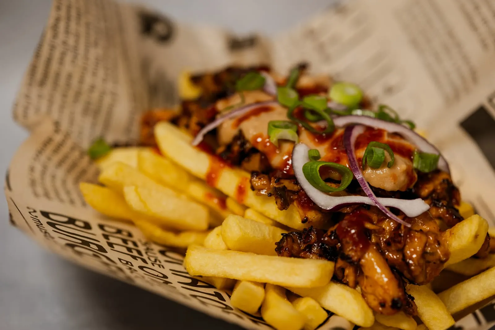 Loaded fries Bali met pulled chicken, pindasaus, sriracha en ui